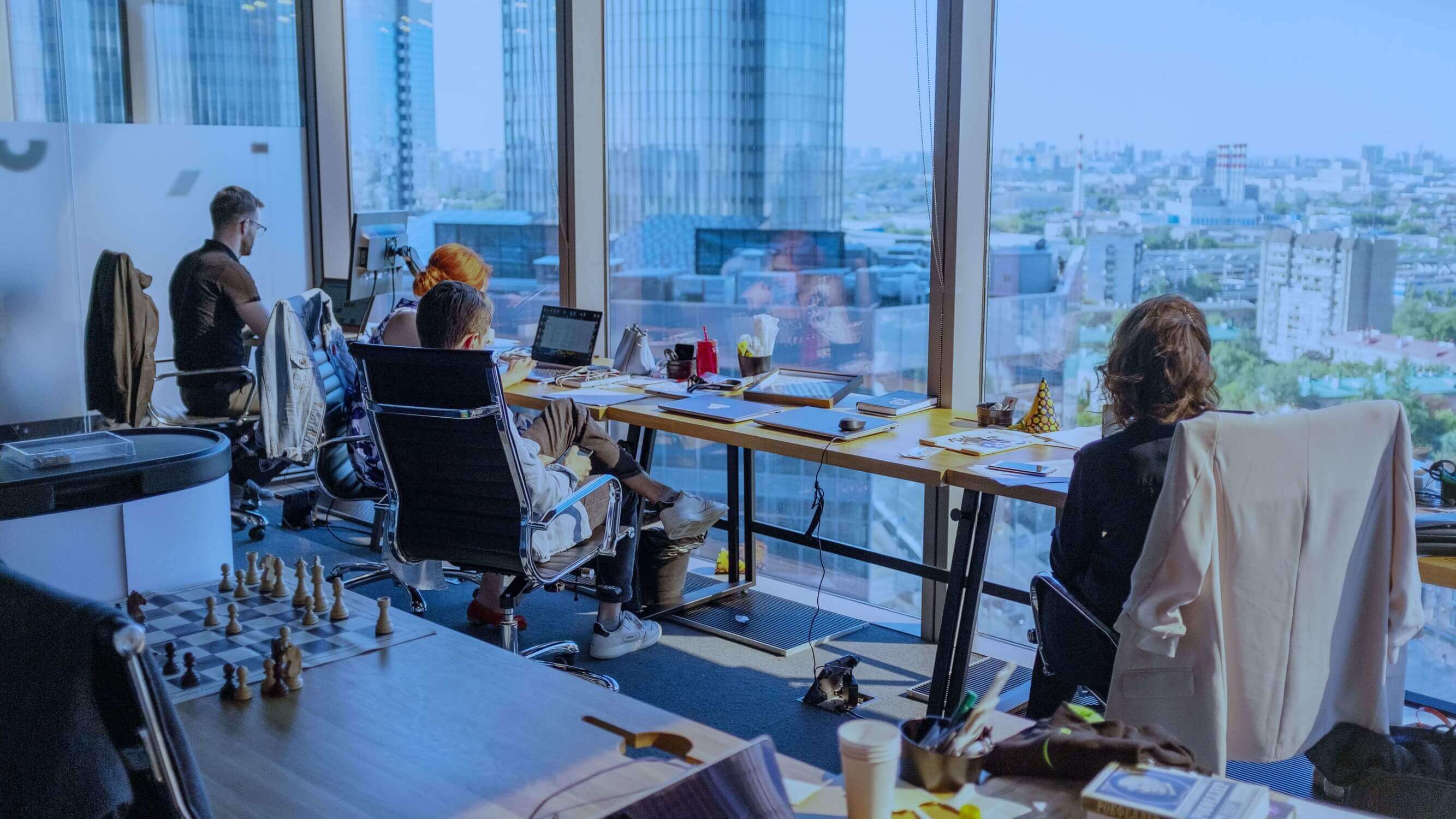 People sitting in the company's office in front of their desks, conducting work using their laptops